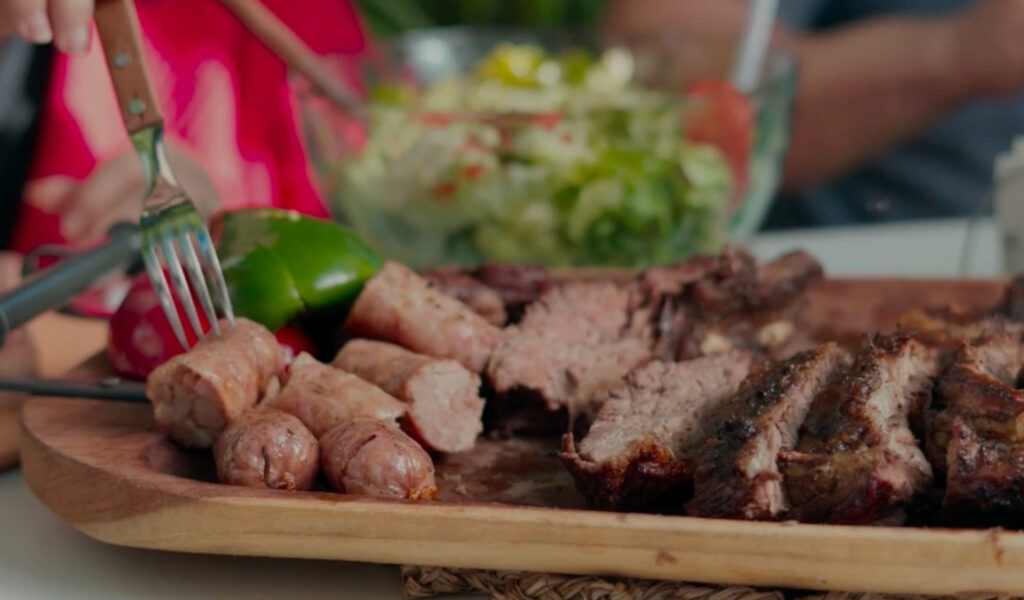 Tabla de asado con vacío, costillar y chorizo recién cocidos, lista para disfrutar al aire libre